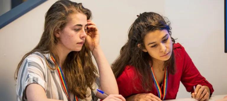 Two students studying at a table with notebooks 