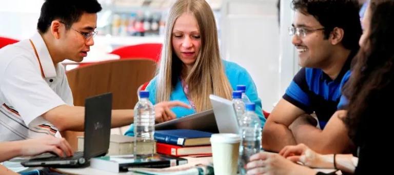 Students sat round a table with laptops and books
