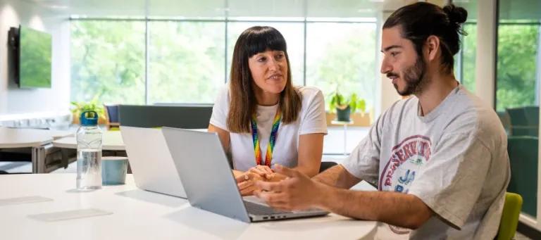 Student with a staff member looking at a laptop 